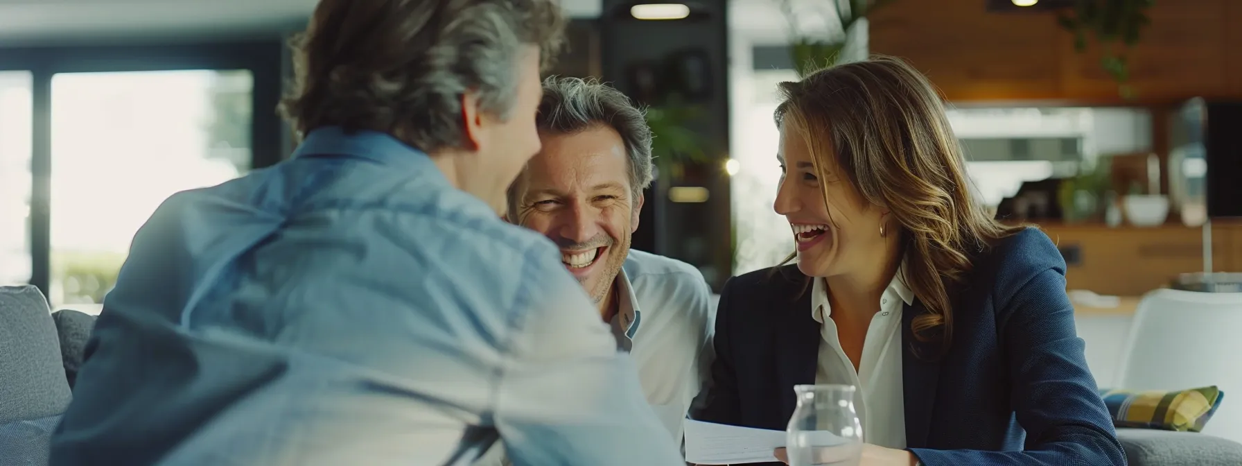 a couple smiling as they review financial documents with a real estate agent in a modern office.