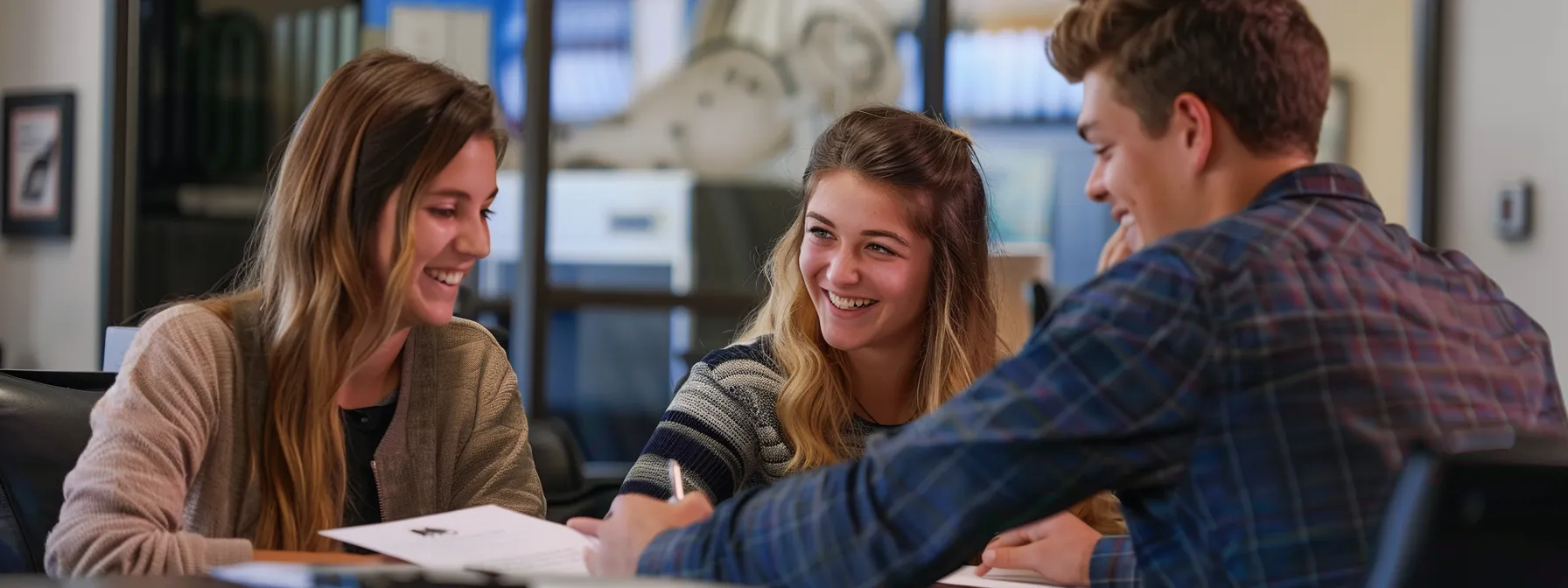 a young couple smiling and signing paperwork with a local lender in a bright, modern office in st. george.