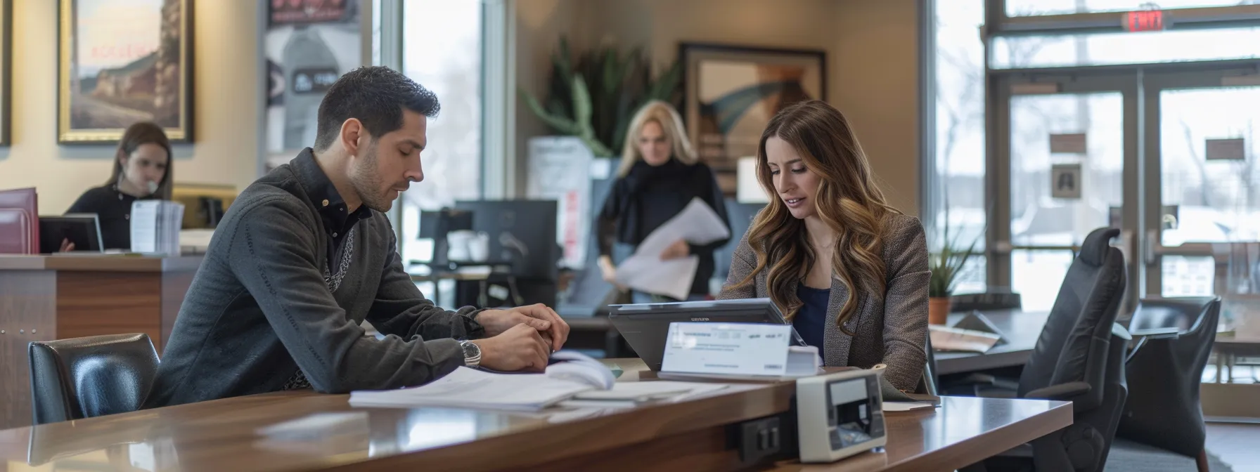 a couple anxiously checking their watches while surrounded by real estate agents and paperwork in a busy office setting.